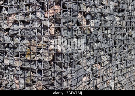 Gabion for a park. Granite stones in a metal mesh. Stock Photo