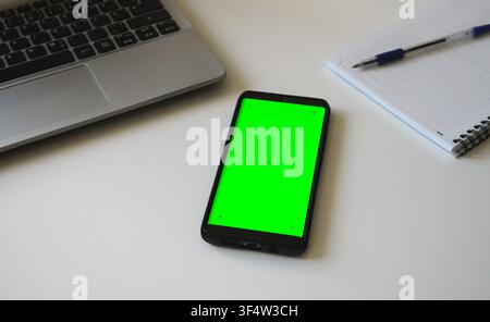 Smartphone with green screen chromakey on white desk. Stock Photo
