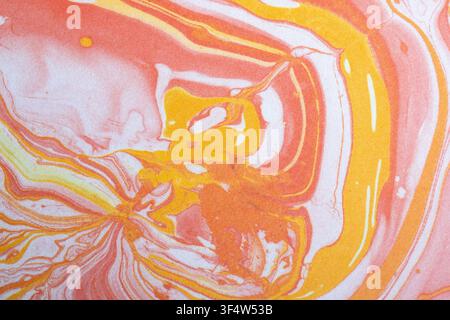 Close-up of peach, yellow, and white card stock featuring a printed fluid art design with swirling marble patterns and flowing organic shapes. High-re Stock Photo