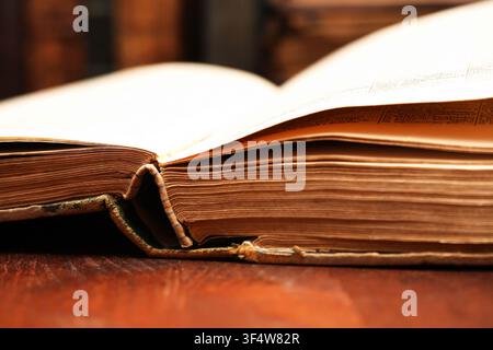 Very old open books on wooden table against background with another books Stock Photo