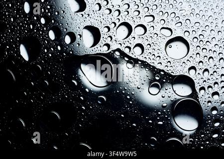 Water droplets forming an abstract pattern on a reflective surface Stock Photo
