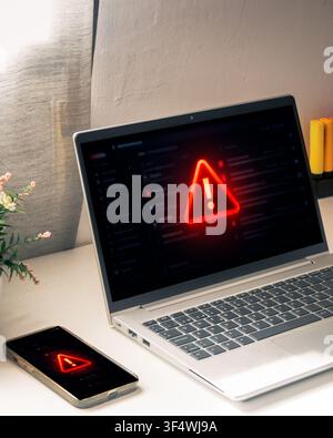 Laptop and smartphone display a glowing red warning symbol, representing a critical cyber threat, security breach or malware alert in a home office. Stock Photo