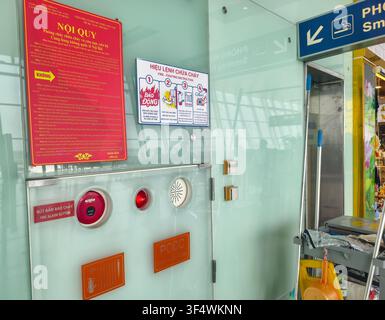 Fire safety station at Hanoi's Noi Bai International Airport features red Vietnamese signage, red alarm button Stock Photo