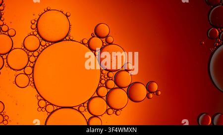 Oil drops floating in water forming an abstract orange and red background texture Stock Photo