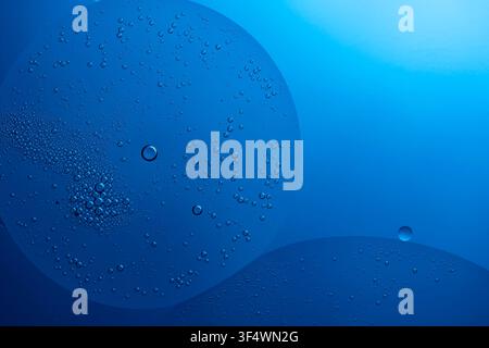 Oil drops creating fluid shapes and abstract bubbles in blue liquid Stock Photo
