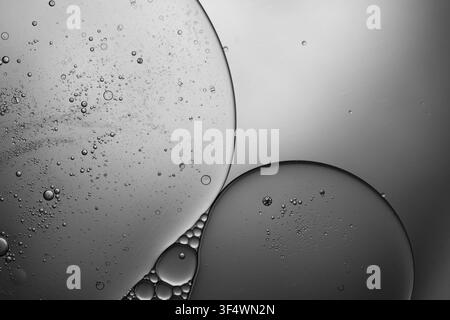Oil drops creating abstract shapes and textures in water, shown in black and white Stock Photo