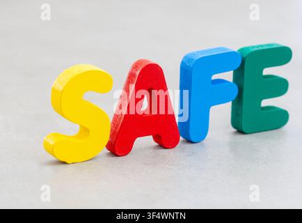 The word "Safe" arranged with colorful wooden alphabet letters on a neutral gray background with copy space. A concept representing protection, securi Stock Photo
