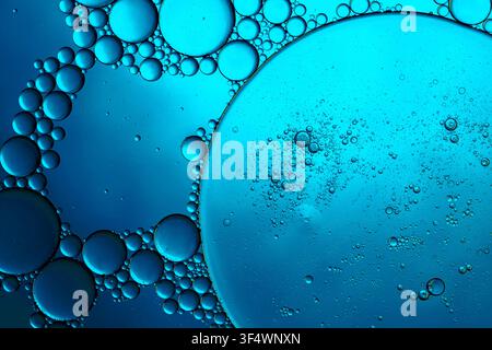 Oil and water creating an abstract pattern with round bubbles and a vibrant blue background Stock Photo