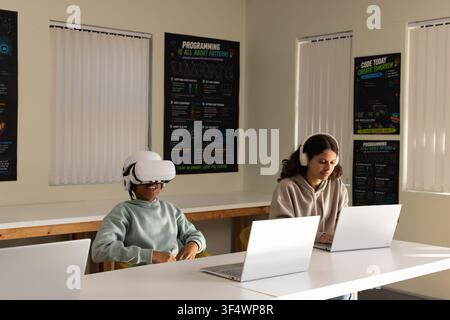 African American students in computer lab, male wearing VR headset, female typing on silver laptop Stock Photo