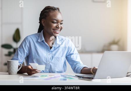 Black Woman Graphic Designer Working With Color Swatches And Laptop At Office Stock Photo