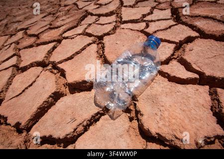 Discarded plastic water bottle on dry cracked earth ground concept of climate change and pollution Stock Photo