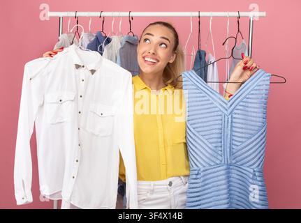 Young woman holding hangers with dress and shirt Stock Photo