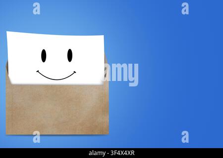 Happy smiley face on white paper inside brown envelope on blue background Stock Photo