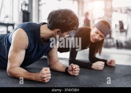 Gym Workout: Plank Pose, Man and a woman performing the plank exercise in a gym sport fitness, Happy smiling. Stock Photo