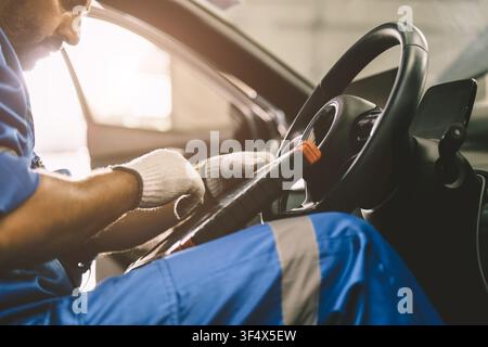 Professional mechanic using OBD2 scanner to inspect vehicle condition in garage. Automotive diagnostic and maintenance service checking engine perform Stock Photo