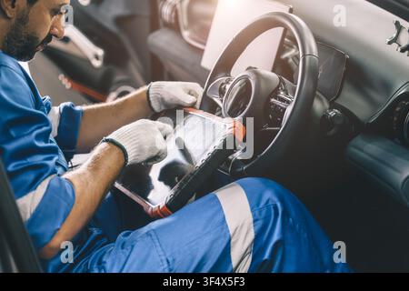 Professional mechanic using OBD2 scanner to inspect vehicle condition in garage. Automotive diagnostic and maintenance service checking engine perform Stock Photo