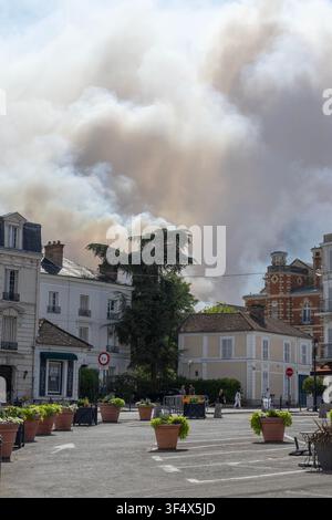Smoke from the wildfire in Fontainebleau forest, France, on 13th July 2026 billows behind houses just opposite Fontainebleau's historic château. Stock Photo