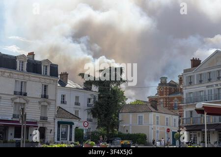 Smoke from the wildfire in Fontainebleau forest, France, on 13th July 2026 billows behind houses just opposite Fontainebleau's historic château. Stock Photo