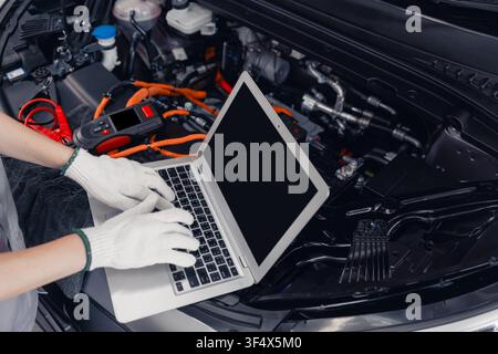 Professional EV Car Service, Worker Using Laptop Monitor Service EV Controller Inverter Diagnosis Checking Inspection with Software. Stock Photo