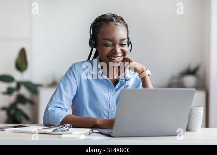 Distance Learning. Young Black Woman In Headset Watching Webinar On Laptop Stock Photo