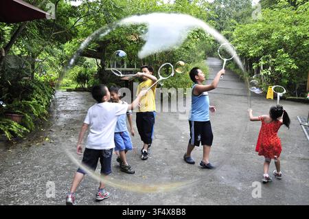 Children playing with giant soap bubbles in a park in Taiwan Stock Photo