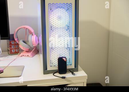 Personal computer with RGB lighting and external SSD connected on a modern desk setup Stock Photo