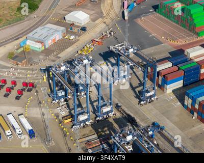 Aerial view of a busy container port featuring large gantry cranes, stacks of colorful shipping containers, and trucks parked in the terminal in the U Stock Photo
