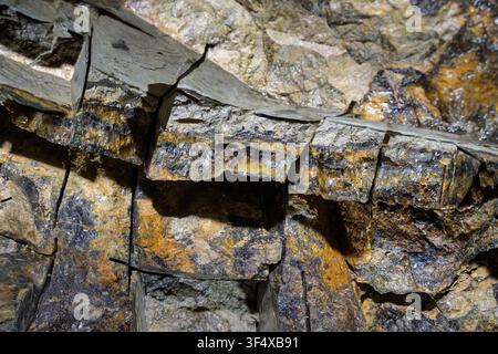 A close-up view shows a natural vein of rare Blue John fluorite stone embedded within the limestone rock strata of Treak Cliff Cavern, Derbyshire Stock Photo