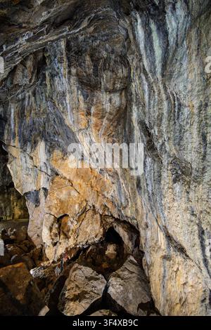 The spectacular Frozen Waterfall flowstone formation cascades down a towering, illuminated limestone rock wall inside the historic Treak Cliff Cavern Stock Photo