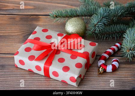 Christmas gift box with red ribbon and red dots and candy cane on wooden background Stock Photo