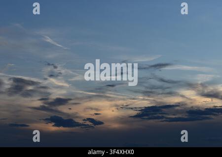 Dramatic sky with soft contrails and dark clouds during late afternoon dusk Stock Photo