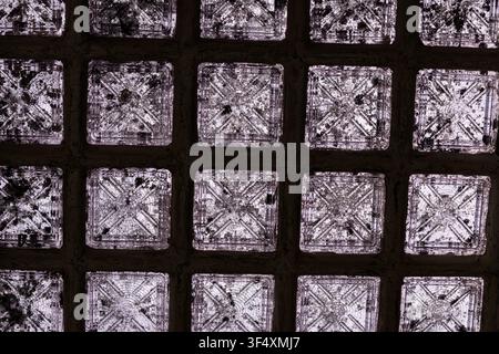 Pattern of translucent glass blocks forming a geometric architectural wall with textured surfaces. Stock Photo