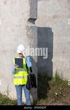 Female architect reviewing plans on a tablet at a concrete construction site Stock Photo