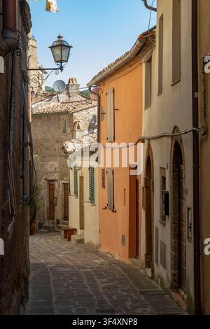 Traditional buildings line a charming Italian alleyway with stone paving and an old lantern Stock Photo
