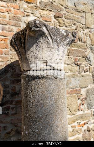 Weathered stone column capital featuring old inscriptions against a rustic wall Stock Photo