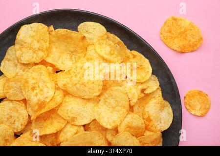Potato chips on plate on pink background. Top view Stock Photo