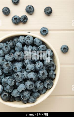 Fresh delicious blueberries in bowl on light wooden background. Top view Stock Photo