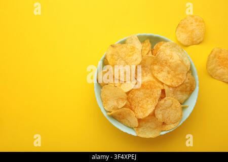 Delicious potato chips in bowl on yellow background. Top view Stock Photo
