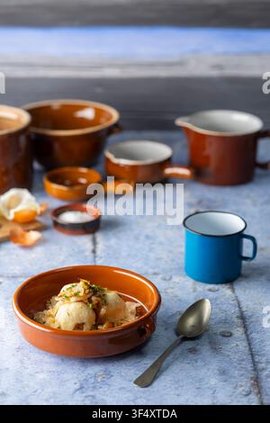 Knodel dumplings served in a rustic bowl with sauerkraut, fried onions, and various pottery Stock Photo