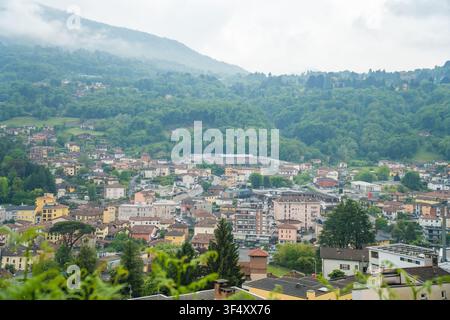 Panoramic misty town view with sports field below mountains, Caslano Stock Photo