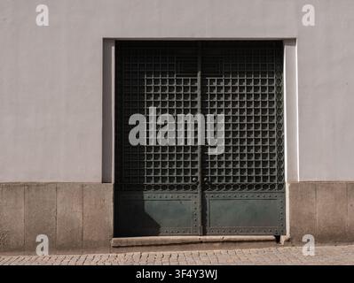 Ornate dark green wrought iron double gate in a minimalist grey wall, Porto, Portugal Stock Photo
