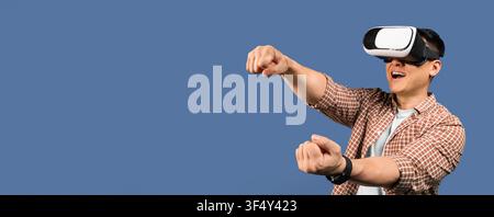 Young Asian Man Using Virtual Reality Headset And Gaming, Excited Expression, Indoor Setting Stock Photo