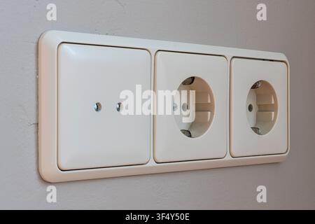 3-fold European wall socket assembly with one cover and two Schuko power outlets Stock Photo