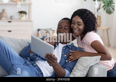 Cheerful black couple using digital tablet at home Stock Photo