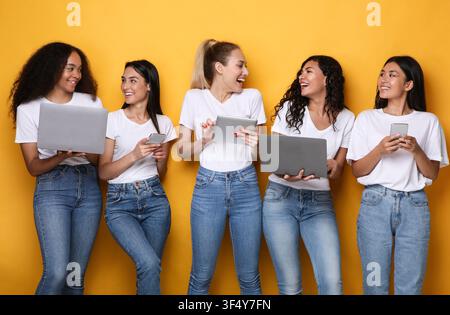 Multiethnic Women Using Gadgets, Computers And Smartphones Over Yellow Background Stock Photo