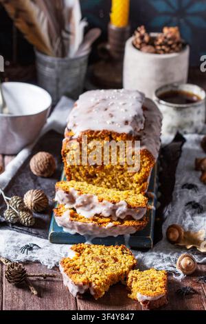 Pumpkin raisin bread with icing, served with tea on a dark background. Halloween concept. Stock Photo