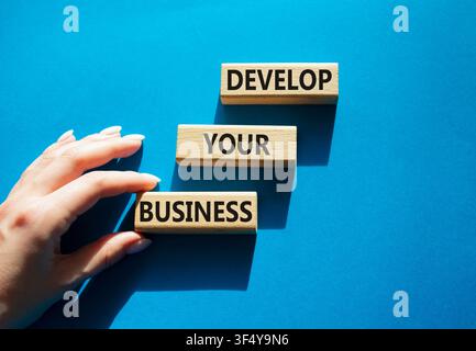 Develop your business symbol. Concept words develop your business on wooden blocks arranged as steps. Businessman hand arranging wooden blocks. Busine Stock Photo