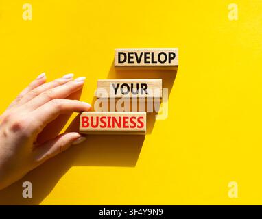 Develop your business symbol. Concept words develop your business on wooden blocks arranged as steps. Businessman hand arranging wooden blocks. Busine Stock Photo