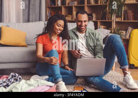 Happy Young Multiracial Couple Relaxing On Sofa While Using Laptop At Home, Lifestyle Concept Stock Photo