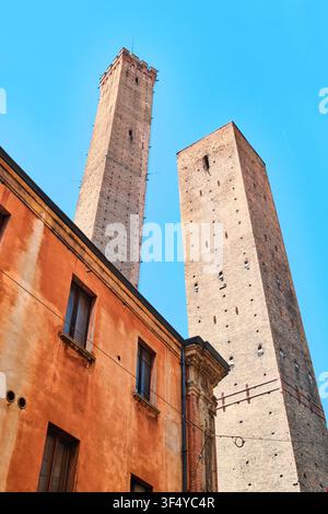 Bologna, Italy - May 2026: Vertical low angle perspective view of Asinelli and Garisenda Two Towers with terracotta building facade Stock Photo